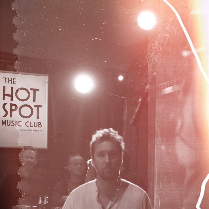 Three men standing under The Hot Spot Music Club sign   
